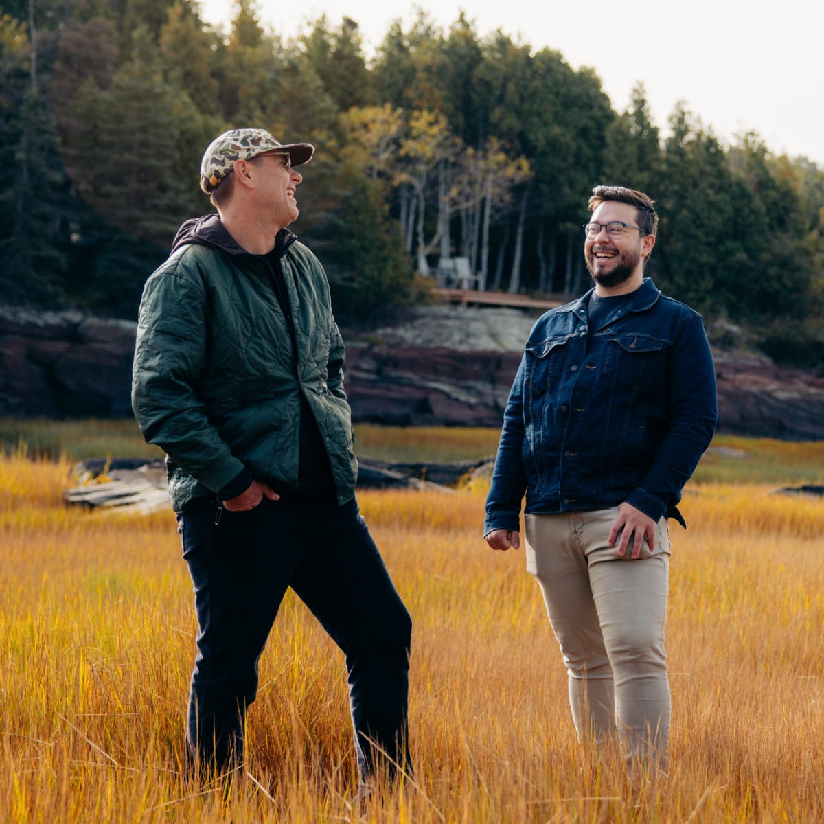 Two men smile at each other during a nature activity.