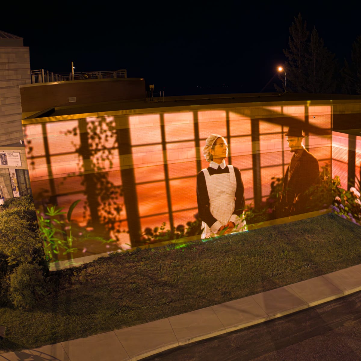 Cité Mémoire - Projection lumineuse d'un homme et d'une femme sur un bâtiment en briques, la nuit
