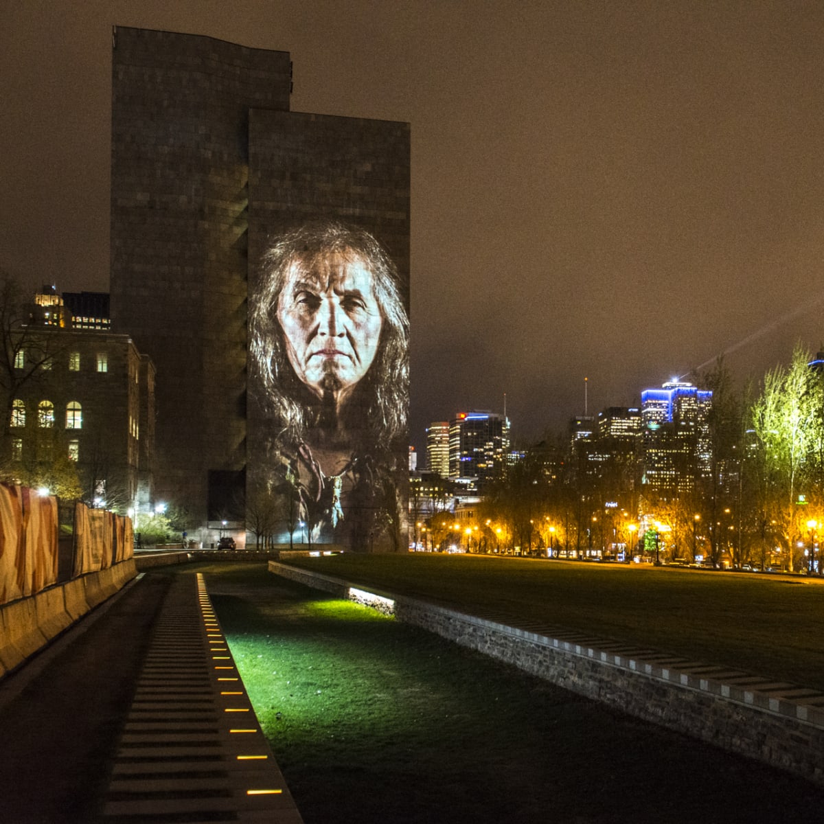 Cité Mémoire - Projection lumineuse d'un individu sur un grand bâtiment sombre, la nuit