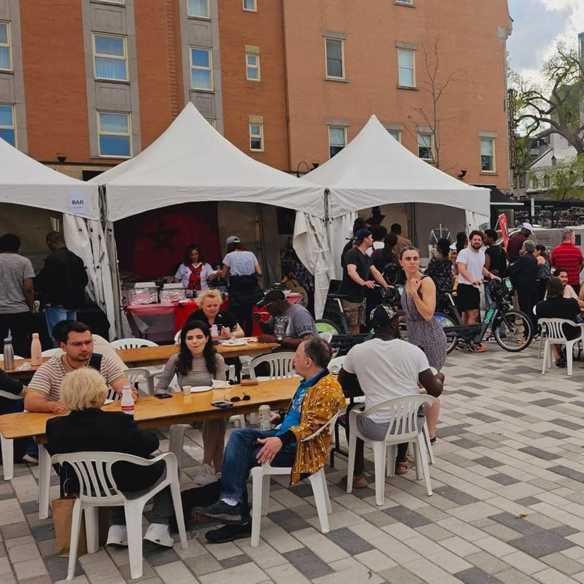 AfriCa Fest - Numerous people sitting at tables, near food trucks and kiosks.