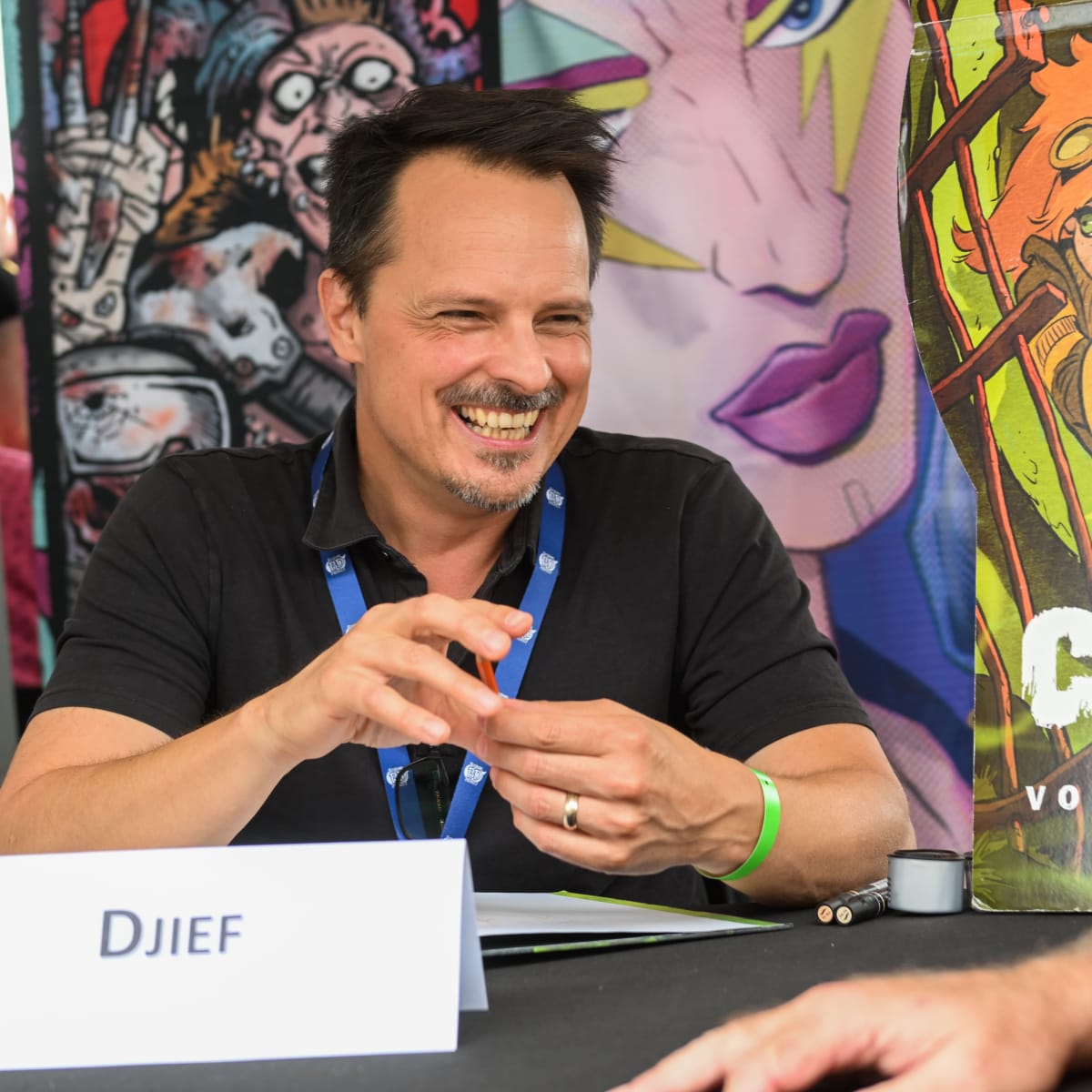 Festival de la BD de Prévost - Un bédéiste est assis avec un autre homme et sourit
