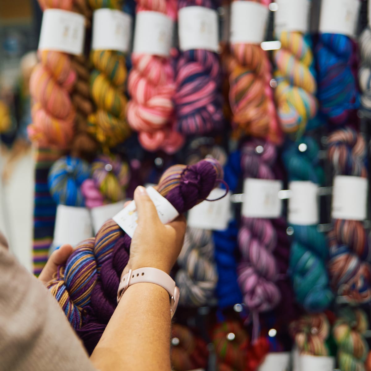 Festival de la fibre Twist - Une personne tient un écheveau de laine devant un présentoir
