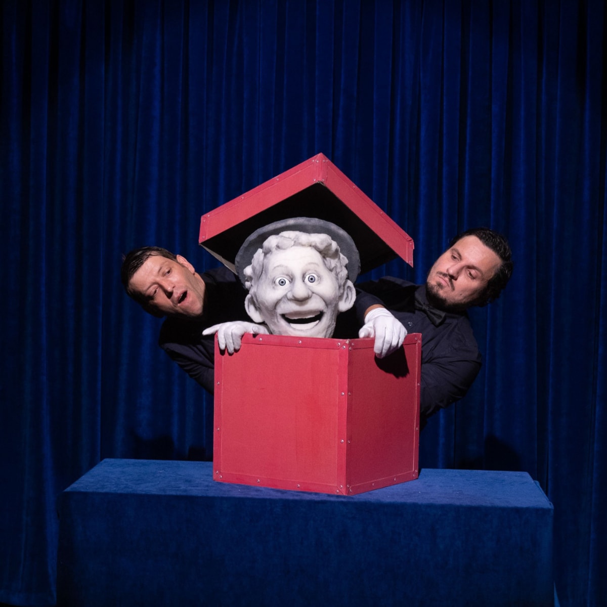 Festival international des arts de la marionnette - A puppet is in a red box. Two men stand next to it.