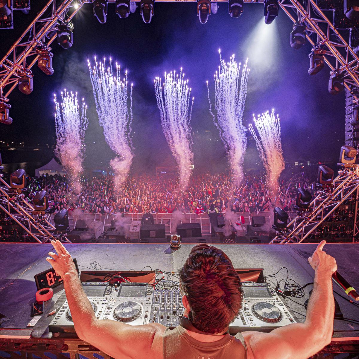 Festival Riverside - DJ sur scène devant une foule en fête, avec jets pyrotechniques.