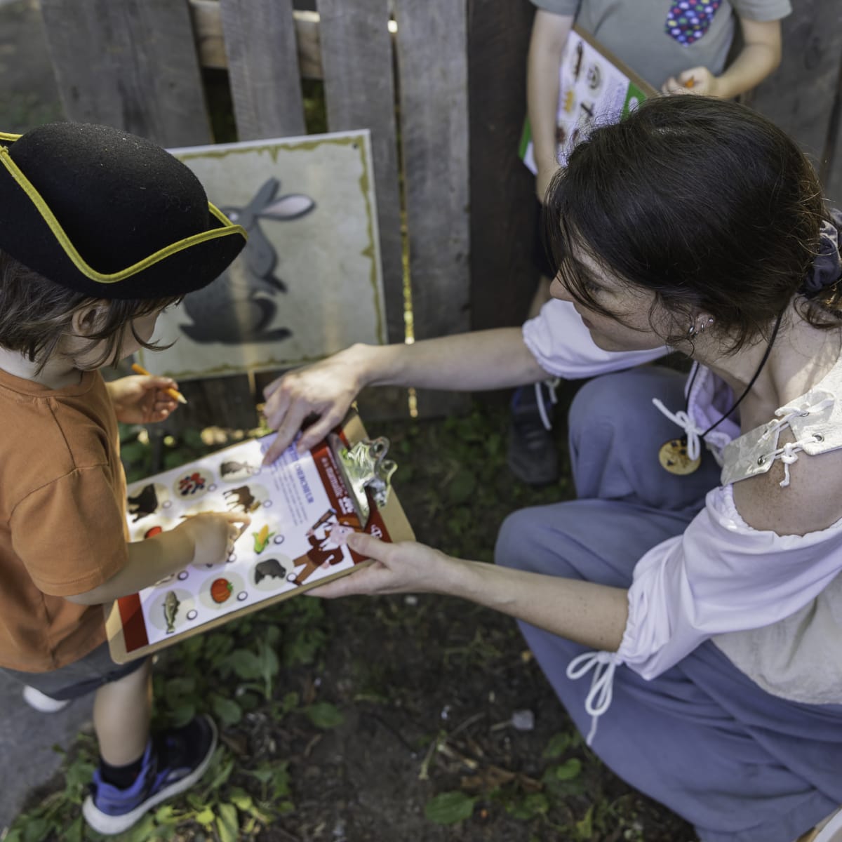 Les Fêtes de la Nouvelle-France - Une femme aide deux enfants