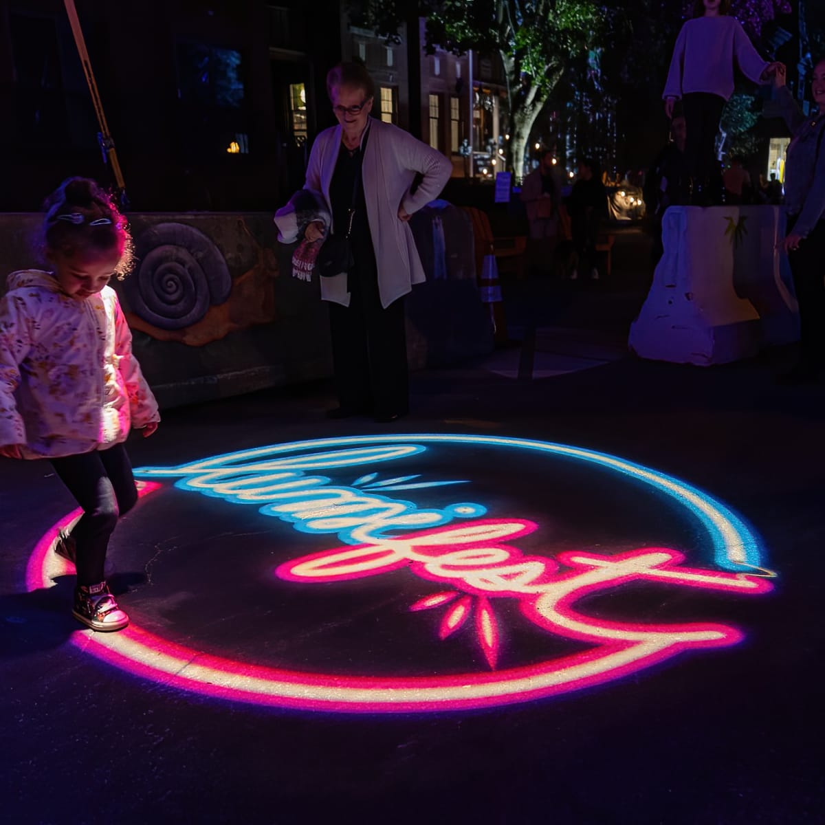 Lumifest Longueuil - A child walking on a luminous projection of the festival logo