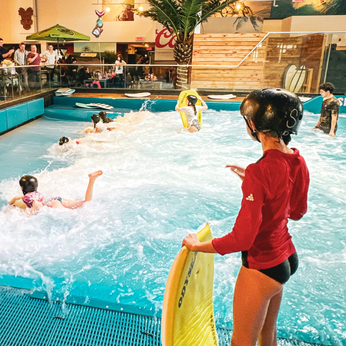 Person holding a boogie board at the edge of the surf pool