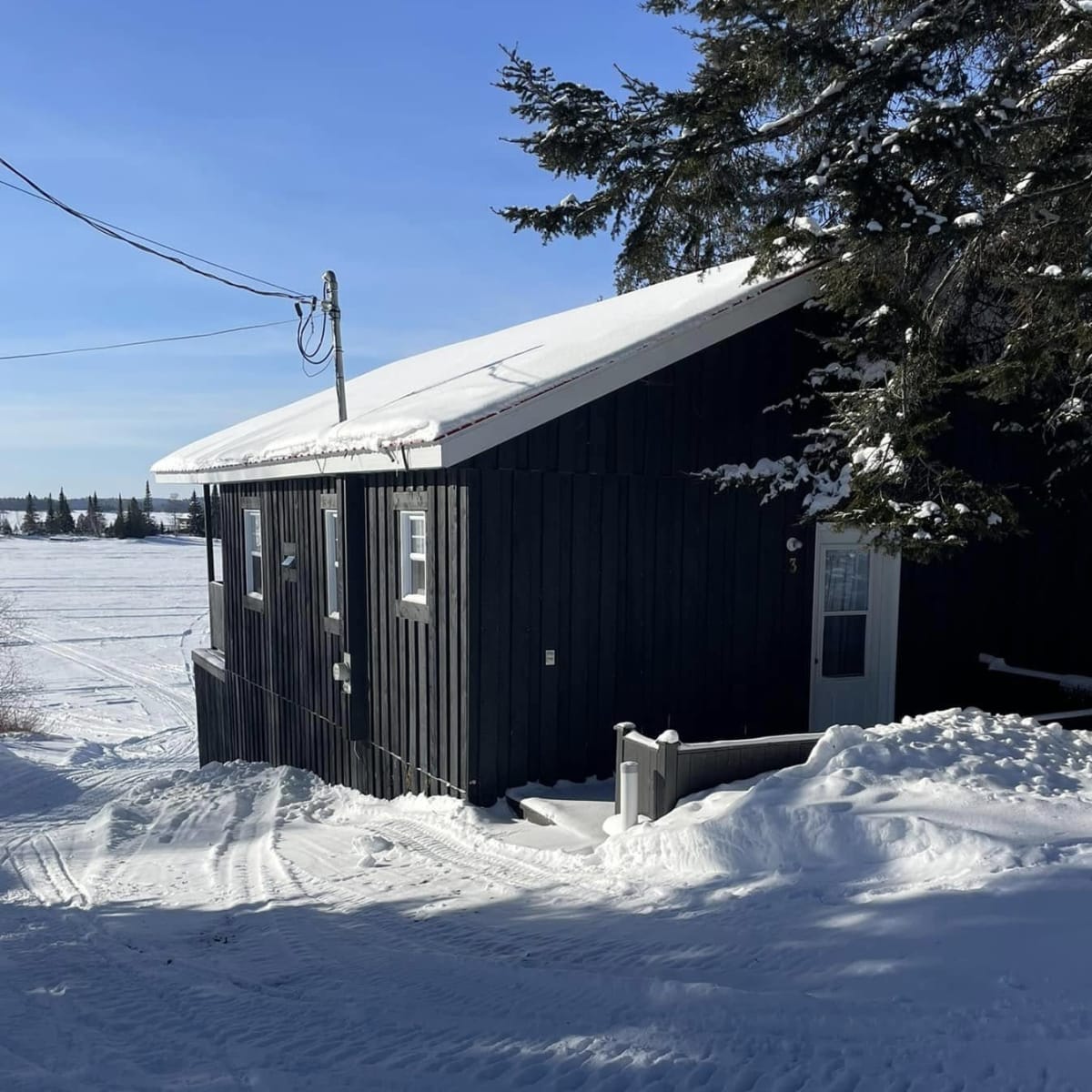 Pourvoirie Fern - Black cabin in winter