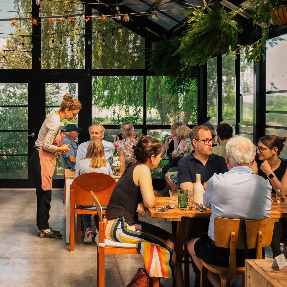 People eating inside a greenhouse at a countrystyle restaurant.