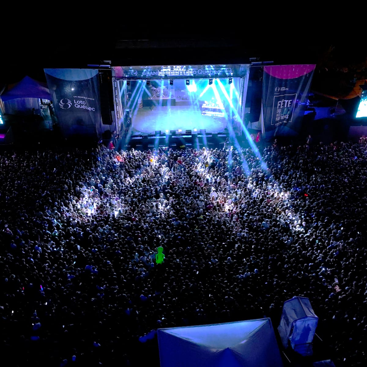 Grande foule devant une scène de spectacle extérieure la nuit à la Fête du Lac des Nations.