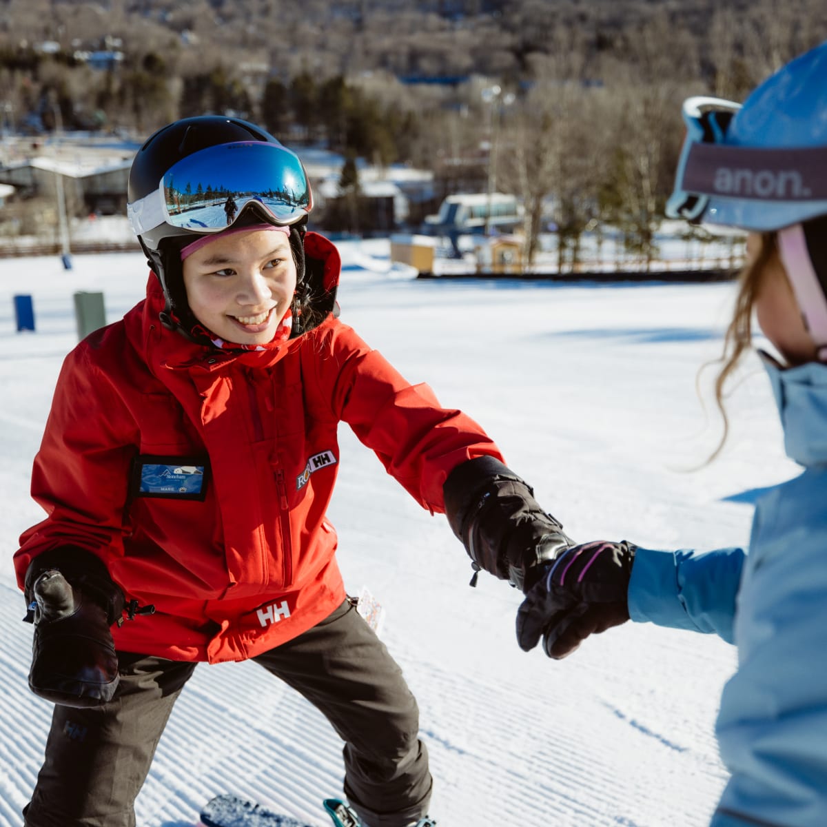 Monitrice tout sourire avec un élève sur les pistes.