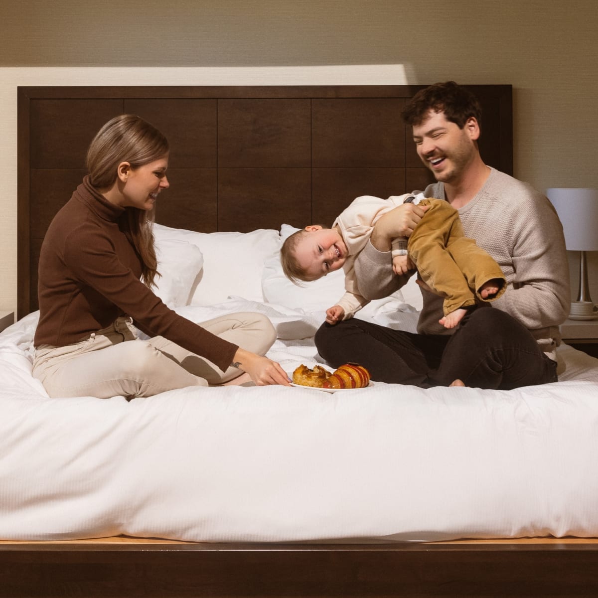 Deux jeunes parents et un enfant sur un lit.