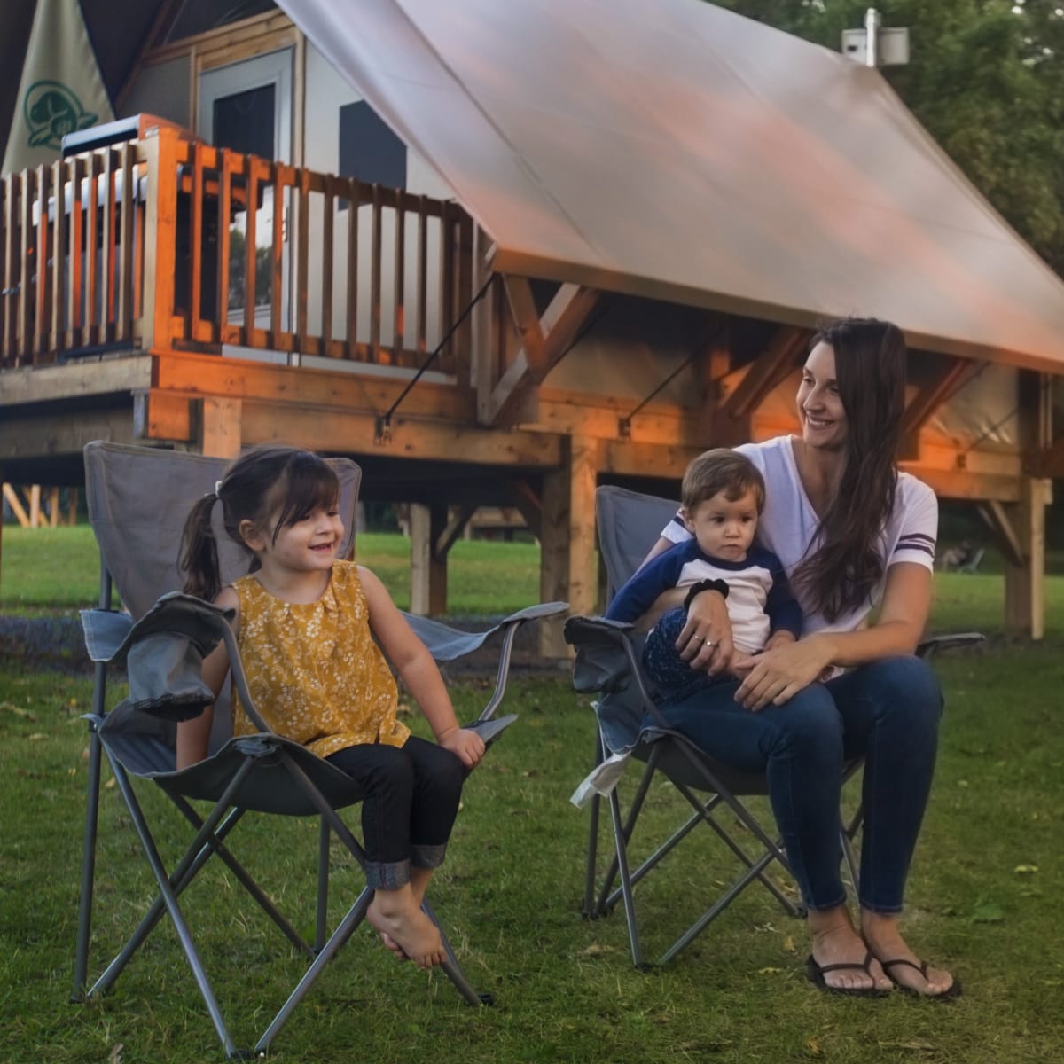 Mère et ses deux enfants au bord du feu de camp devant un prêt-à-camper