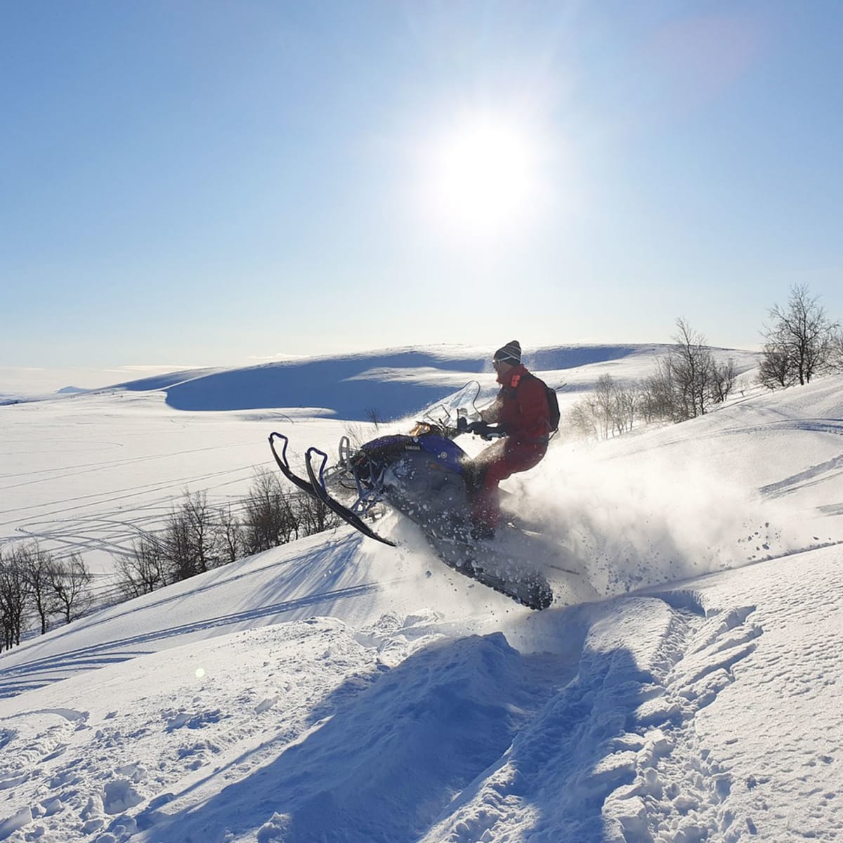 Person snowmobiling through a vast snow-covered landscape.