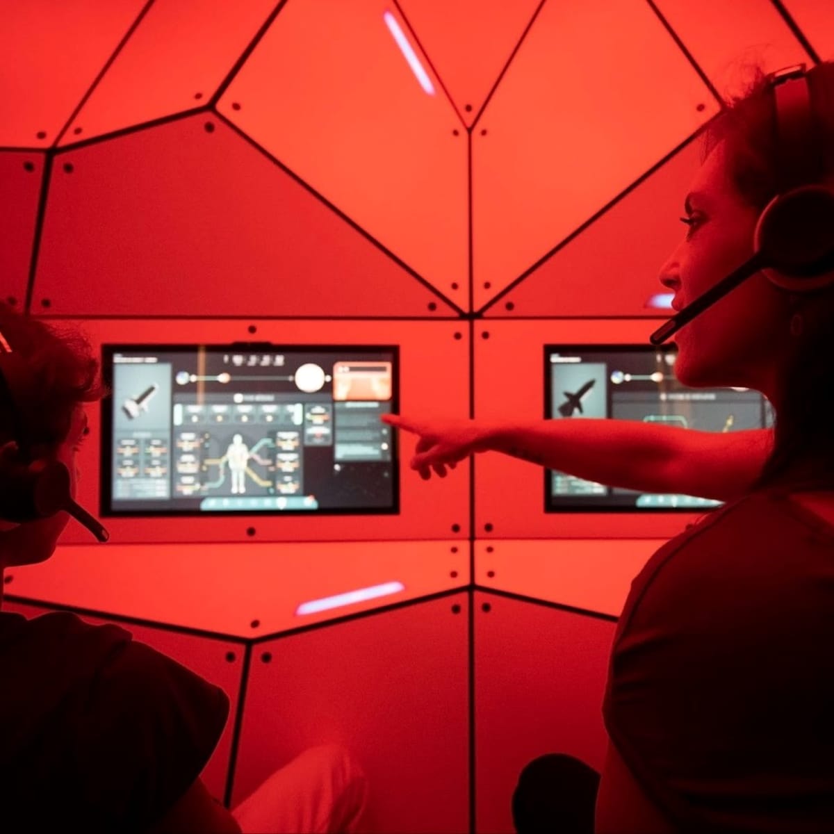 Mother and son wearing headphones sitting in front of screens at the space exhibit.