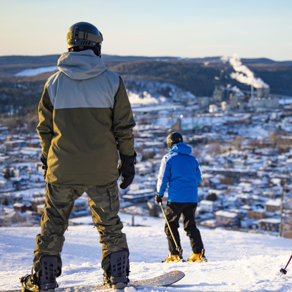 Father, son and daughter on a ski hill looking at the downtown area at the foot of the hill.