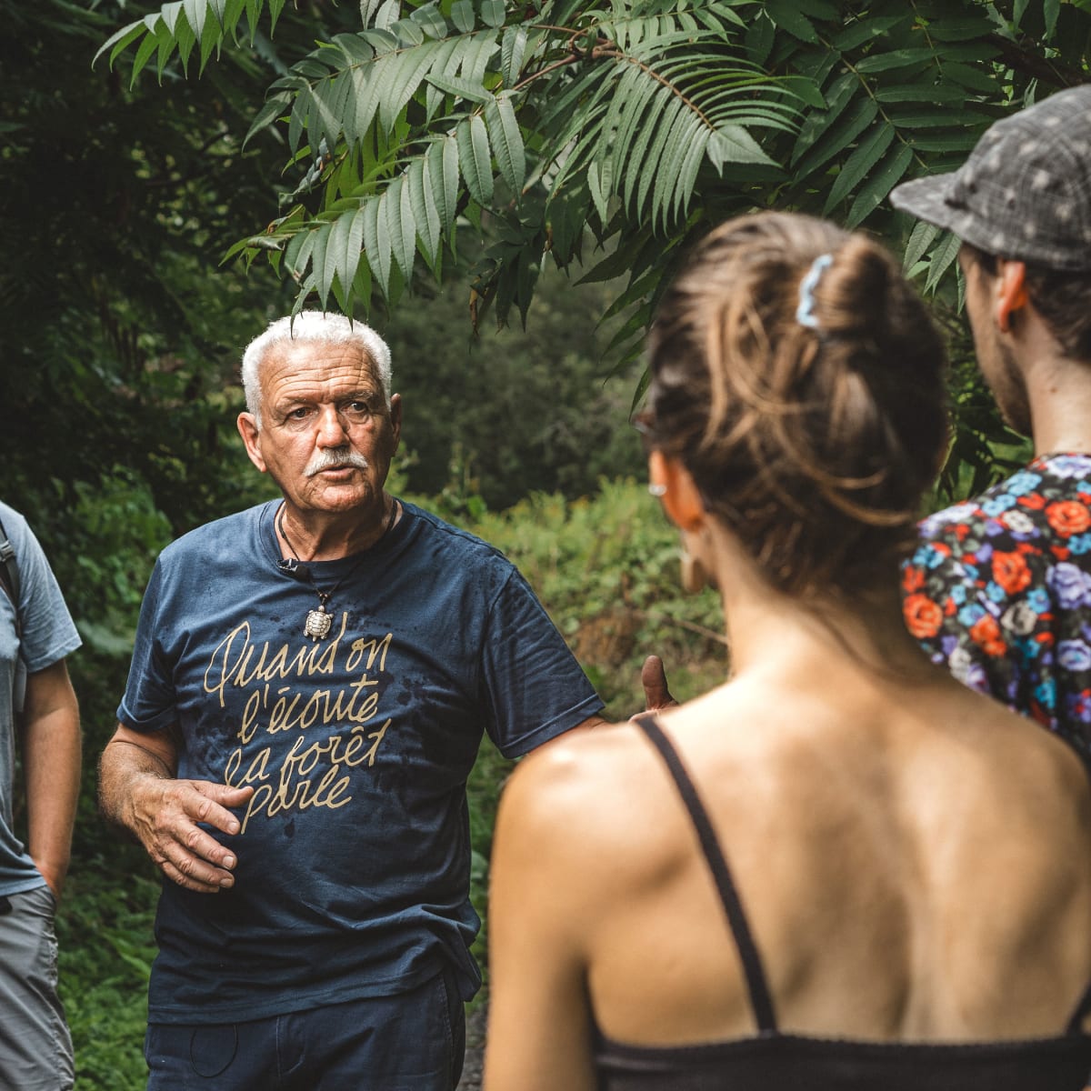 Group of people gathered around an elder in the forest