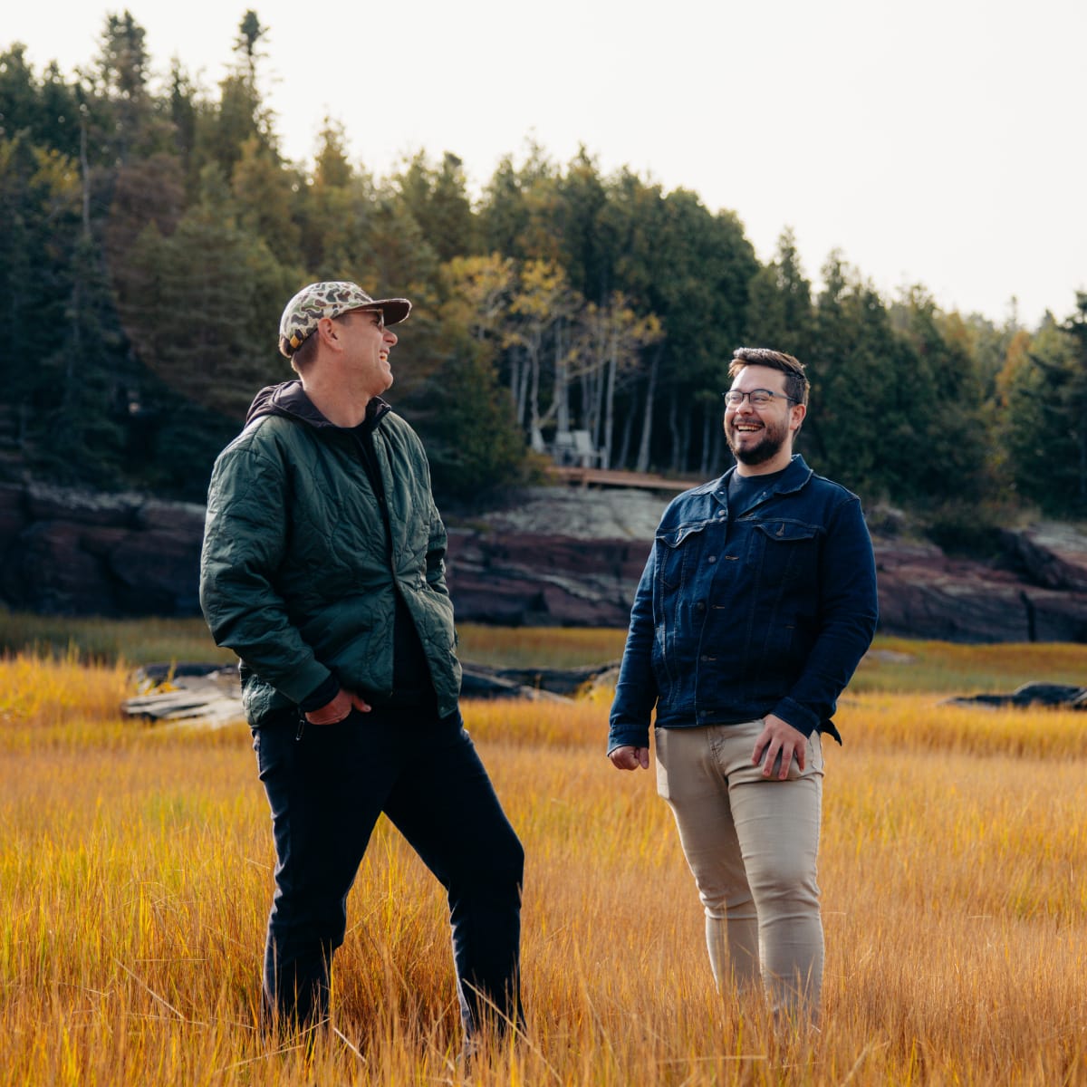 Two men smile at each other during a nature activity.