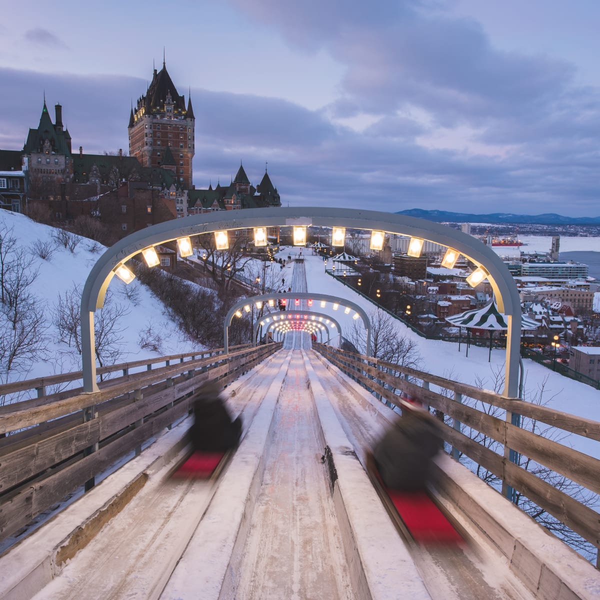 2 glisseurs sur la glissade à côté du Château Frontenac en hiver.