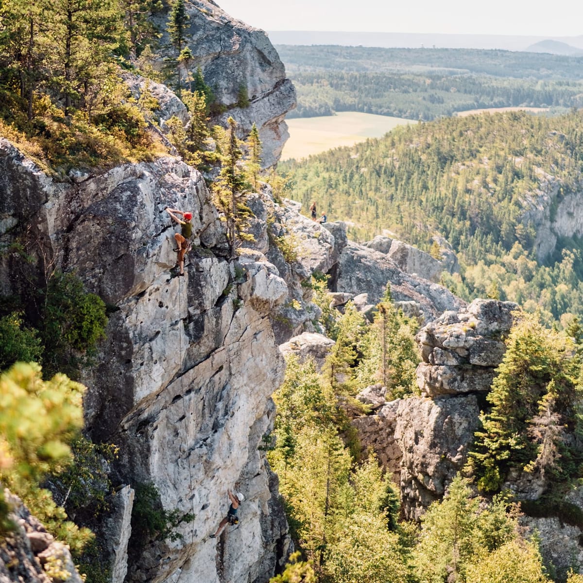 Two people climbing a rocky headland.