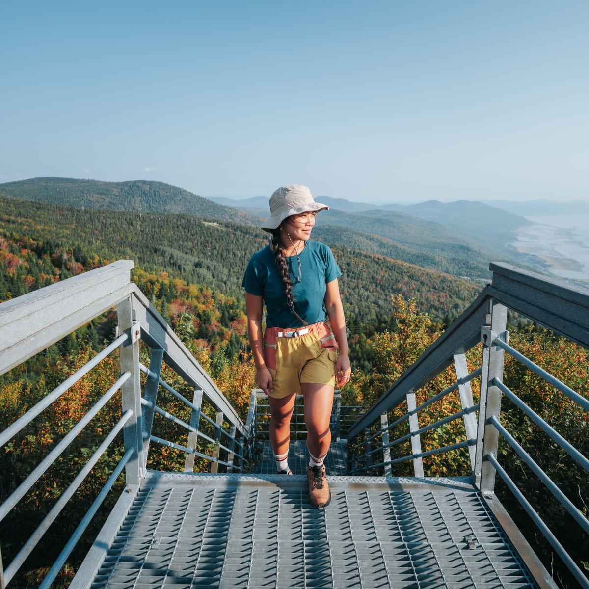 Woman hiking, at the top of a staircase on a mountainside.