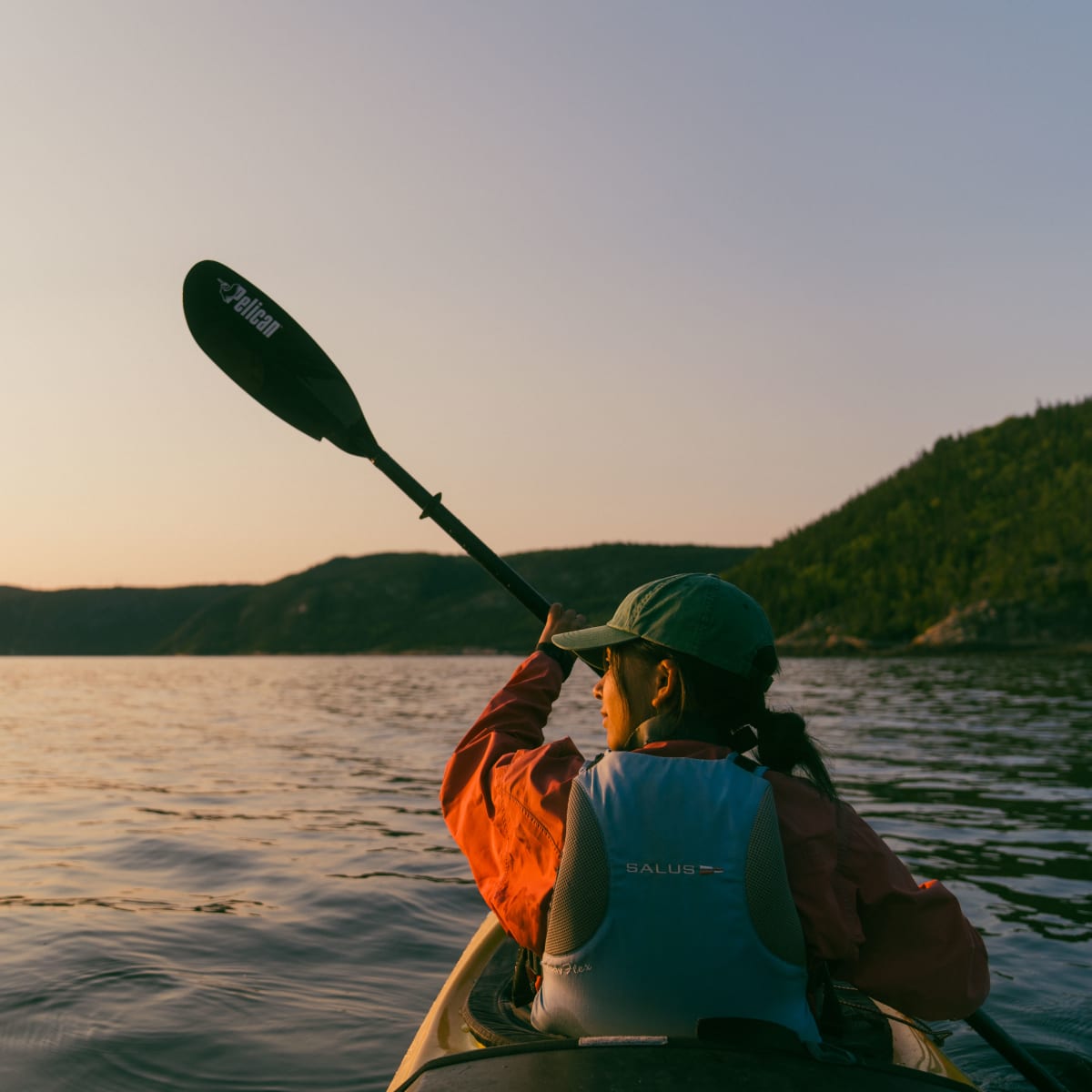 Woman kayaking on the Saguenay Fjord at sunset.