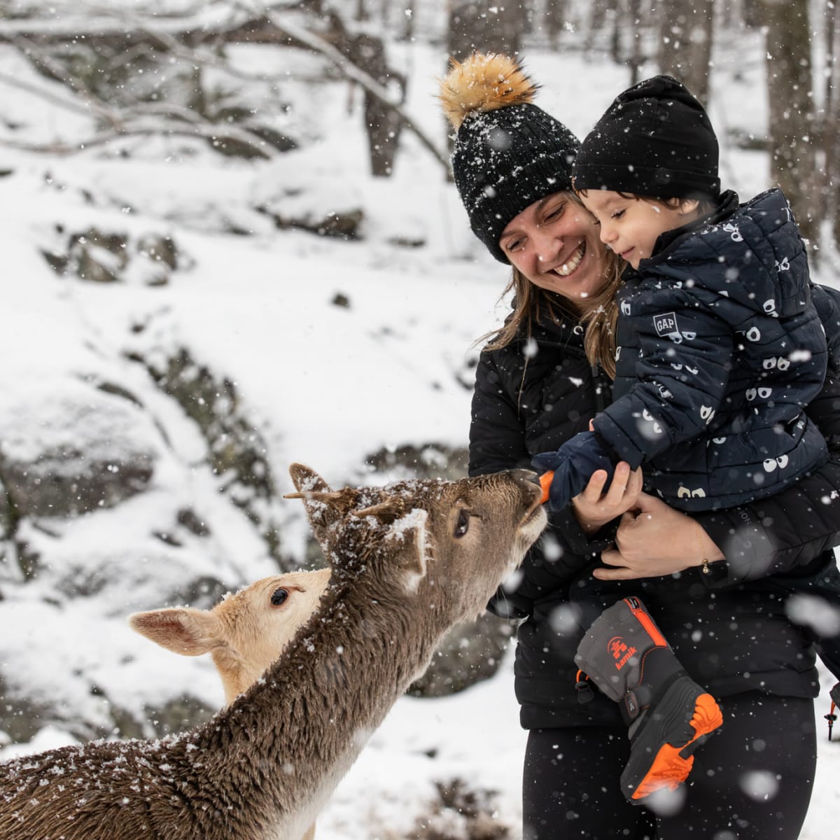 Mère et fils qui flattent un chevreuil au Parc Oméga.