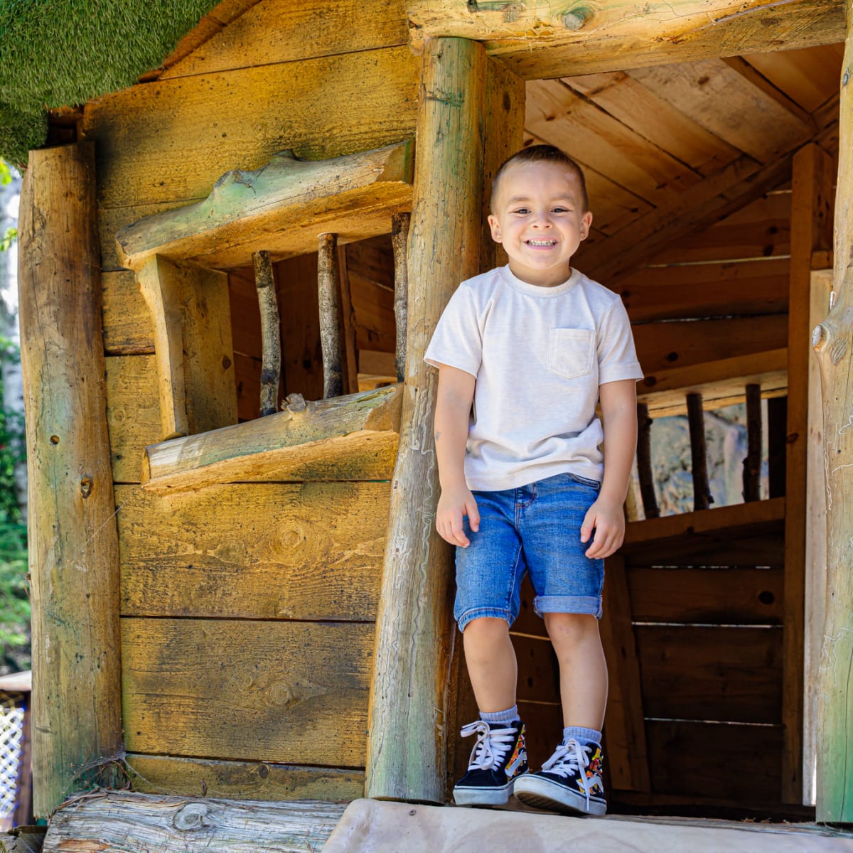 Young boy in front of a wooden cabin