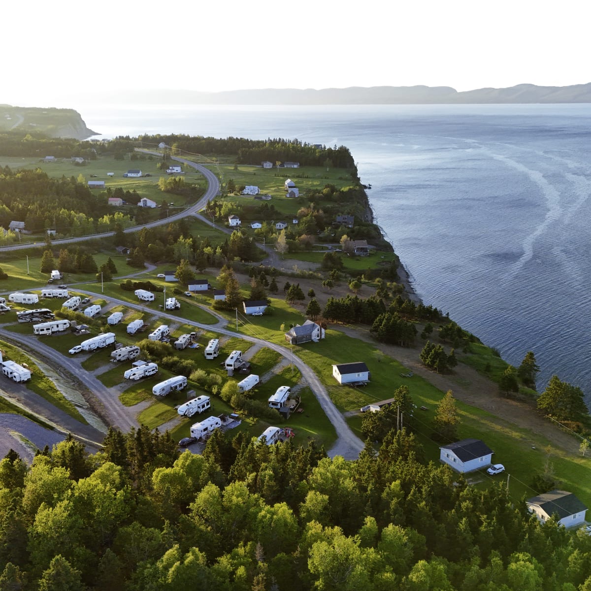 Aerial view of various types of accommodations, all located on a cliff top right by the water.
