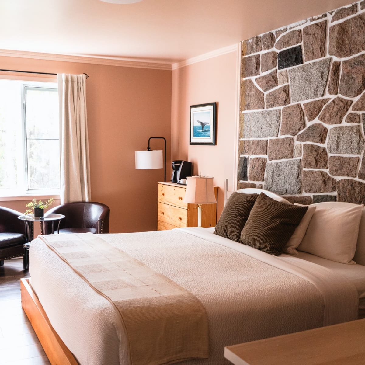 Chambre rose avec un mur de pierre à l'Auberge La Rosepierre.