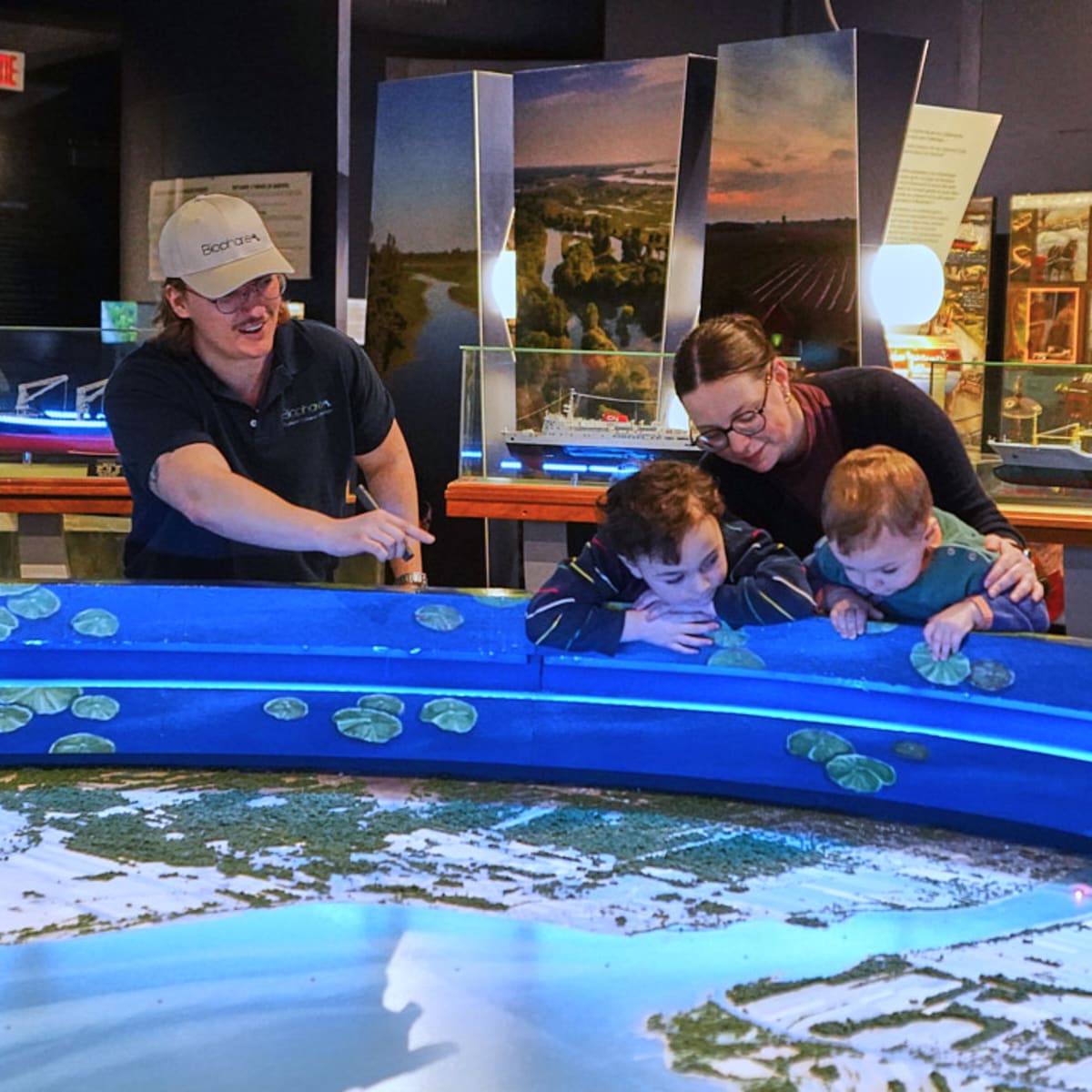 Une mère avec ses jeunes enfants regardant une expositions lors d'une visite guidée.