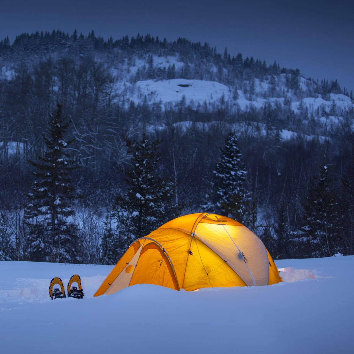 Winter camping in a tent at night in Quebec.