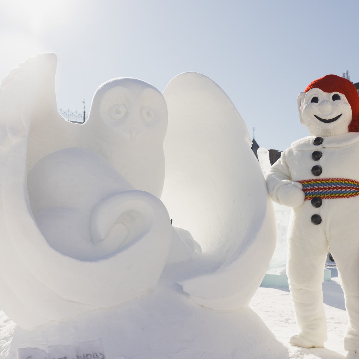 Québec Winter Carnival - Bonhomme Carnaval next to a snow sculpture