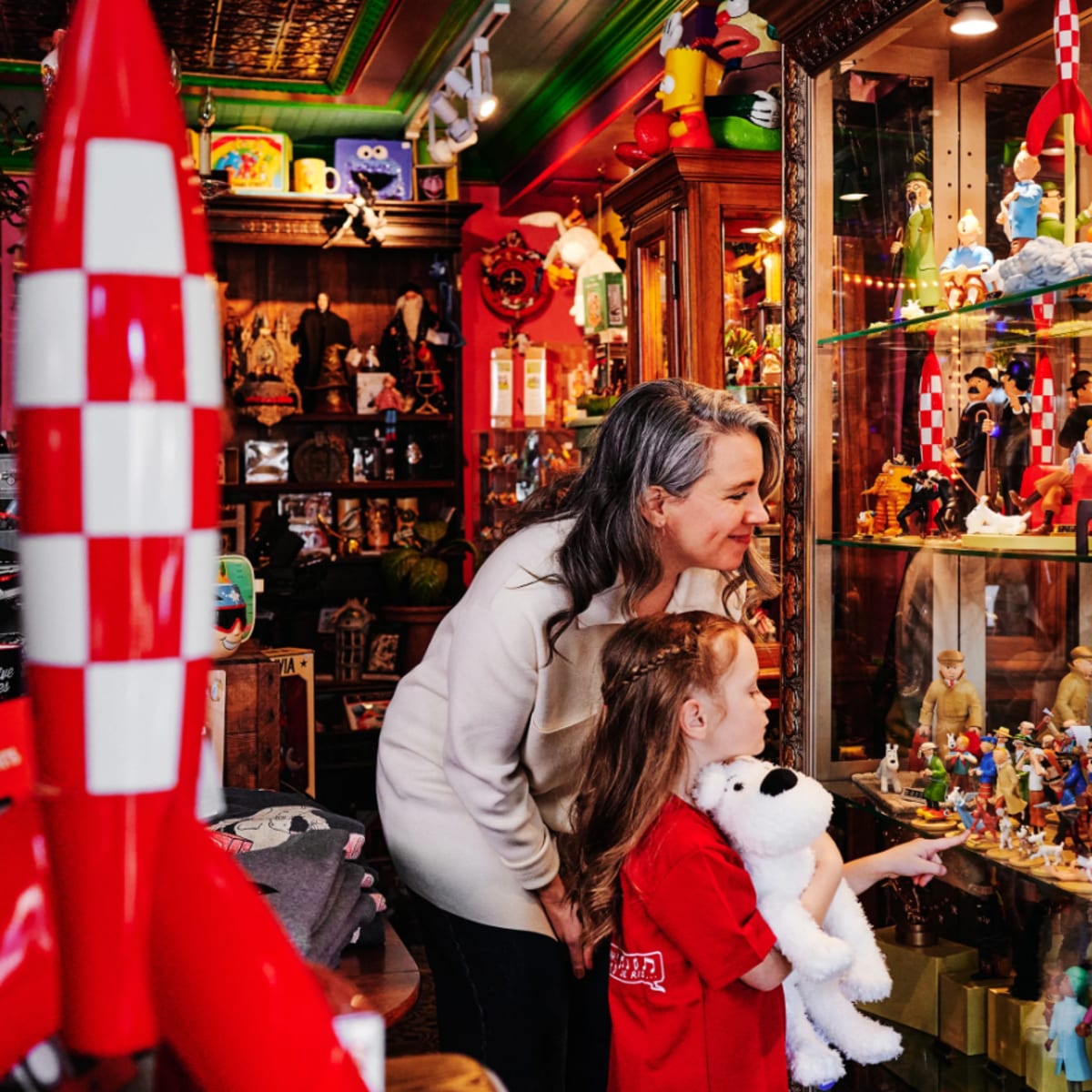 A woman and a girl in the store looking at the Tintin collection. 