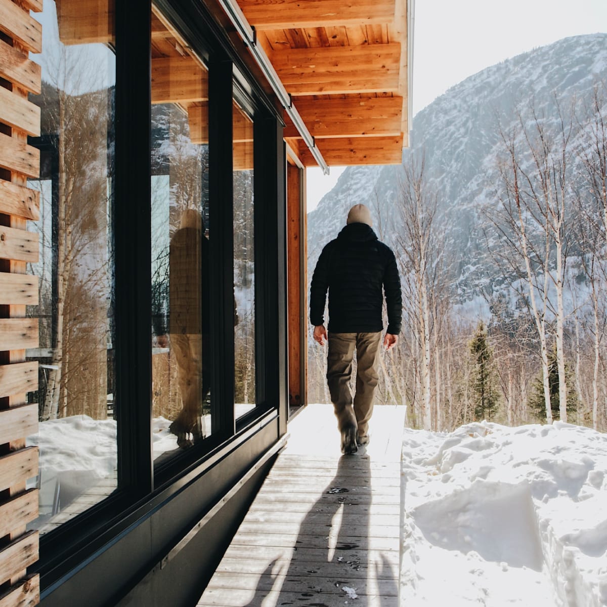 Un homme à l'extérieur d'un chalet du Parc national des Grands-Jardins en hiver.