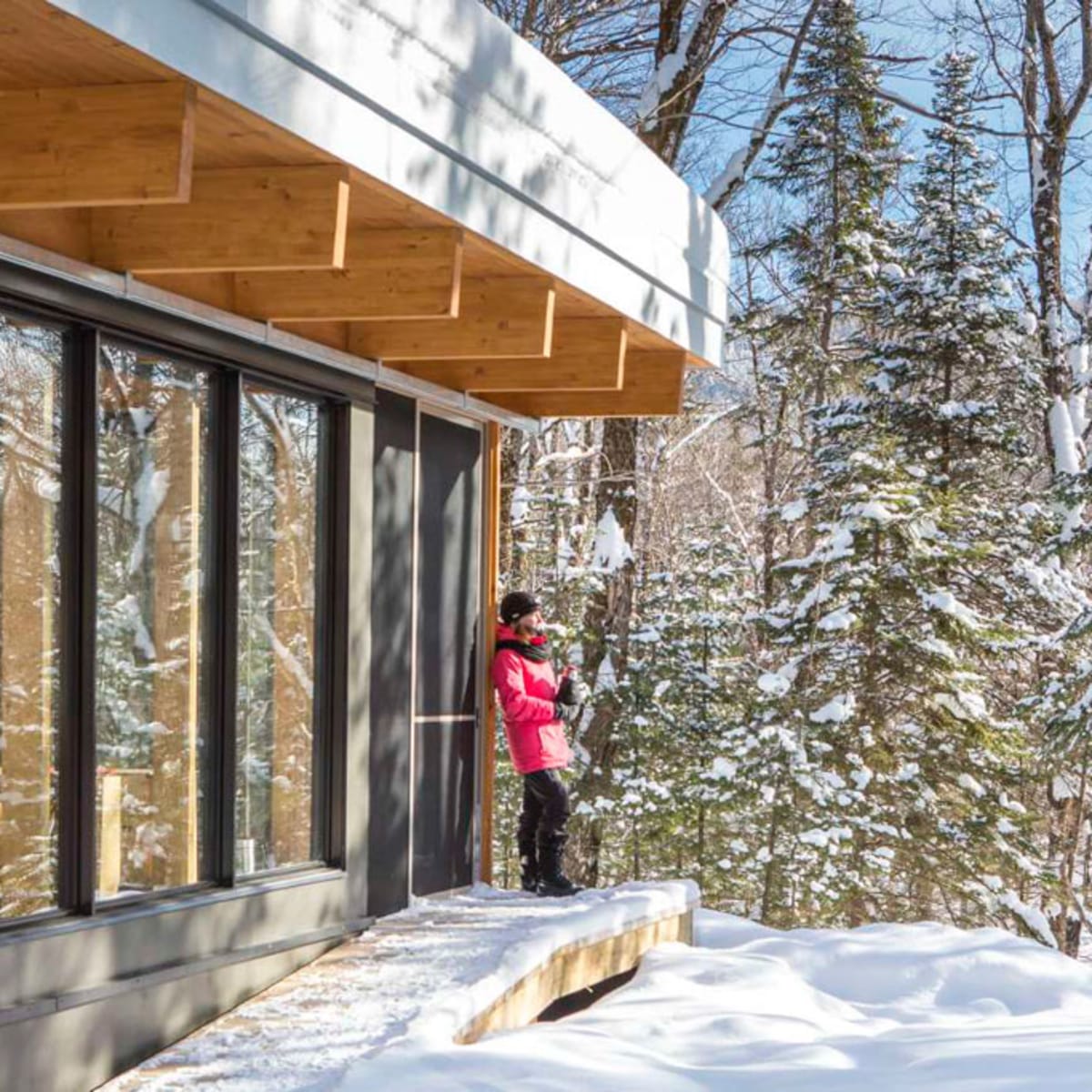 Une femme à l'extérieur d'un chalet du Parc national du Mont-Mégantic, en hiver.