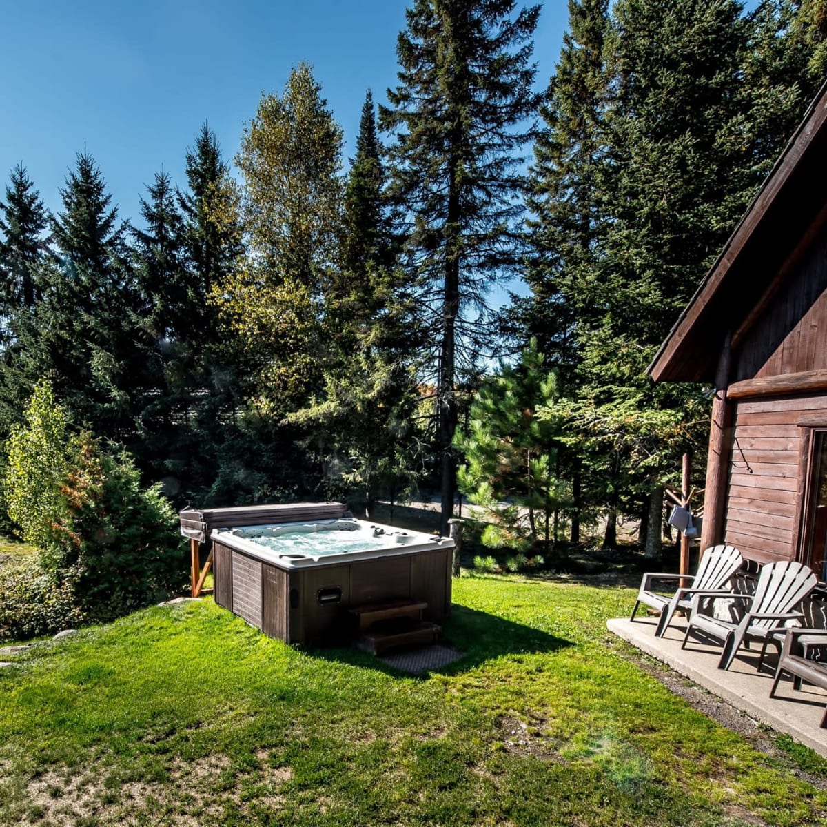 A hot tub and Adirondack chairs outside one of the cottages at Chalets Royal Laurentien.