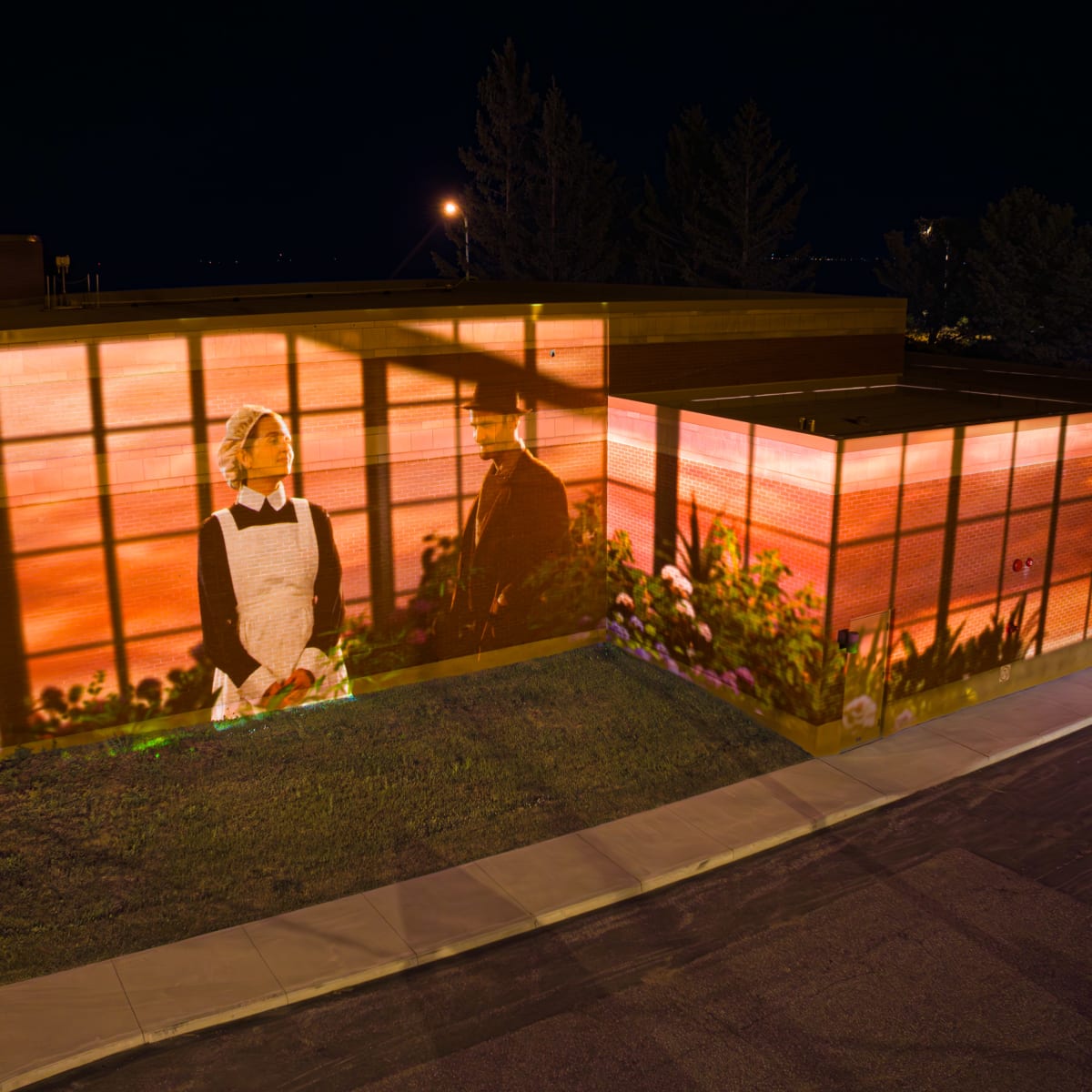 Cité Mémoire - Light projection of a man and a woman on a brick building at night