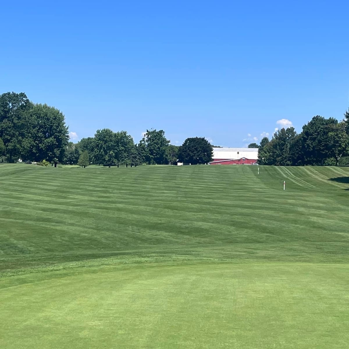 A grassy fairway under a cloudless blue sky at the Club de golf Saint-Anicet.