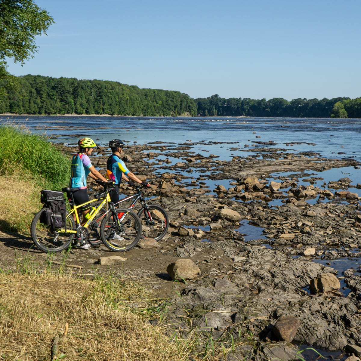 Two cyclists stopped near a body of water.