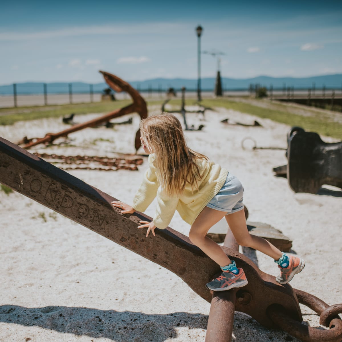 Girl playing on old anchors.