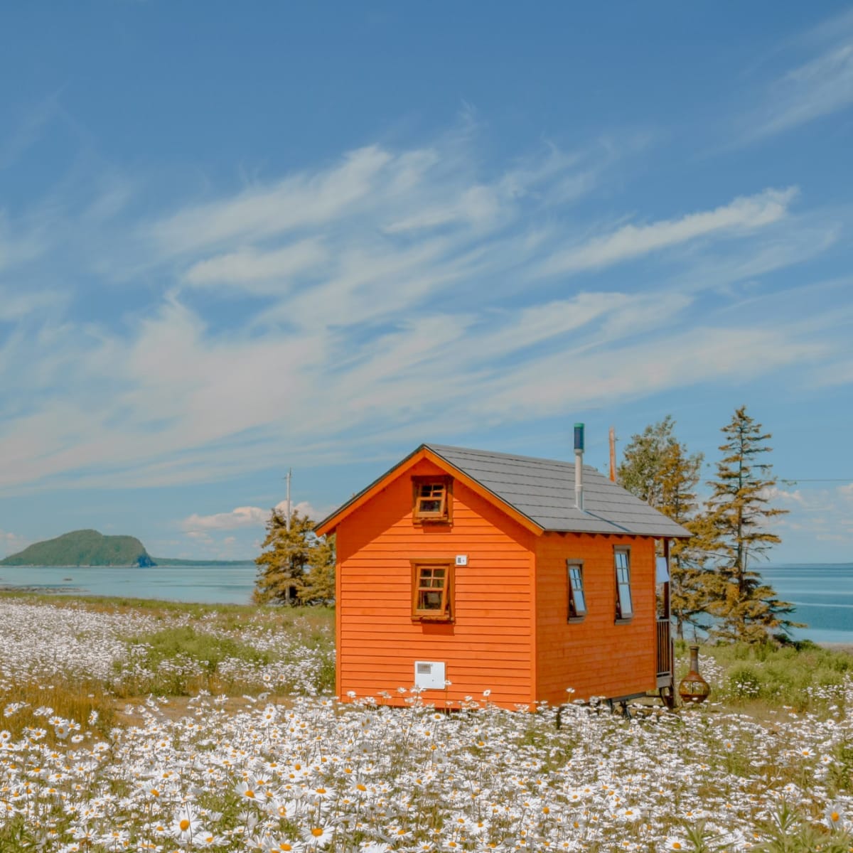 Orange tiny house by the St.Lawrence river in spring. 