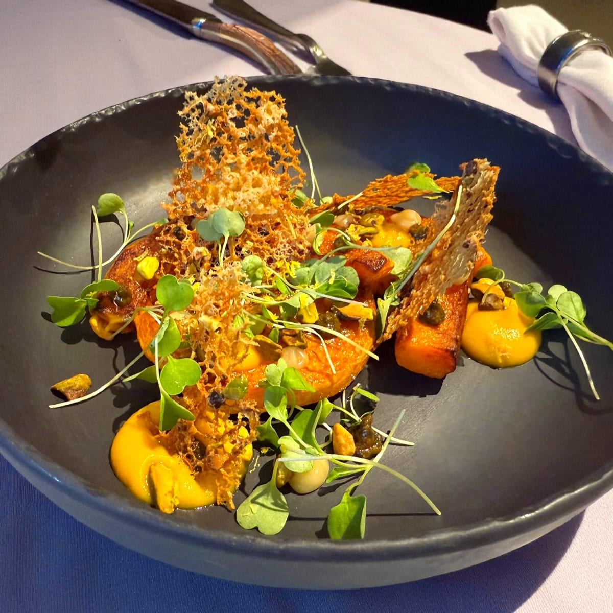 Colourful dish of roasted butternut squash on a black plate.