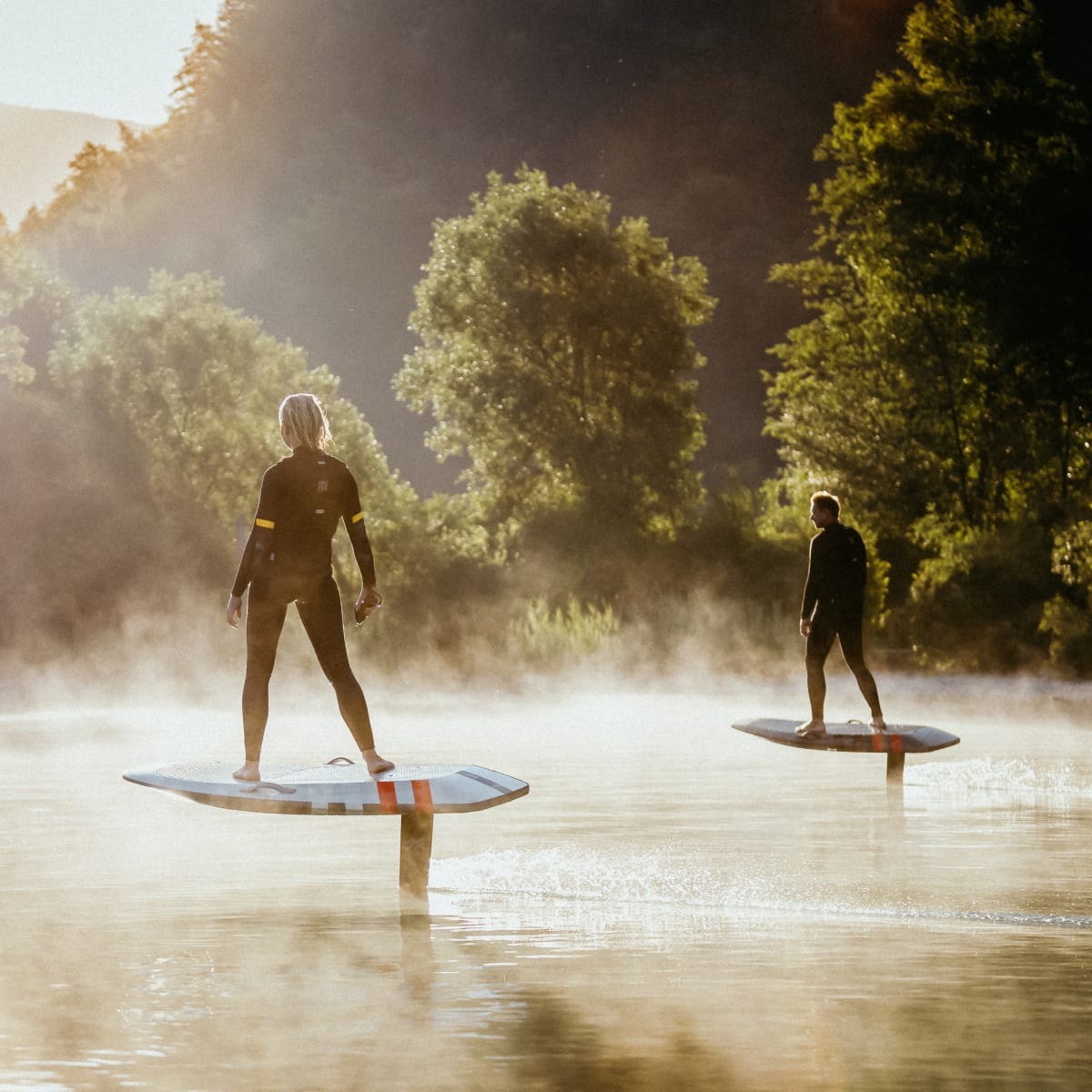 Two people on electric surfboards.