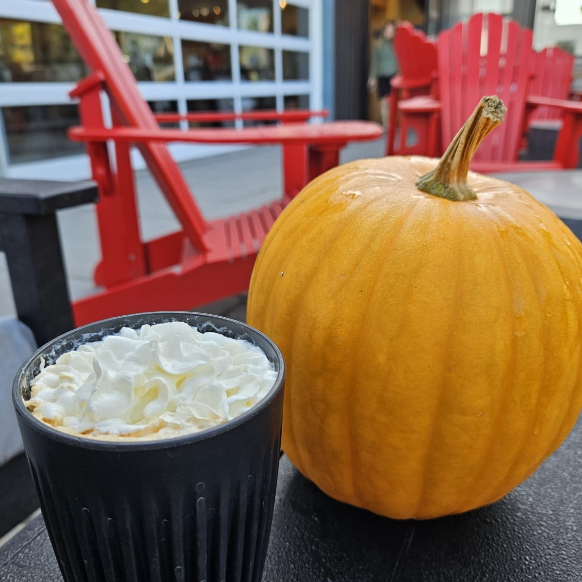 Latté à la citrouille à la crème fouettée et citrouille sur une terrasse de café.