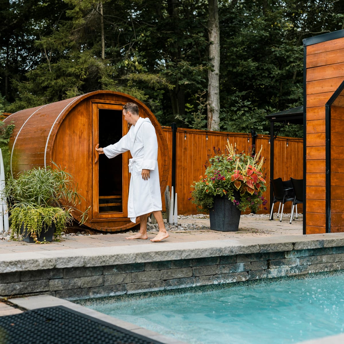 A man in a bathrobe opening the door to an outdoor sauna at Hôtel Montfort.