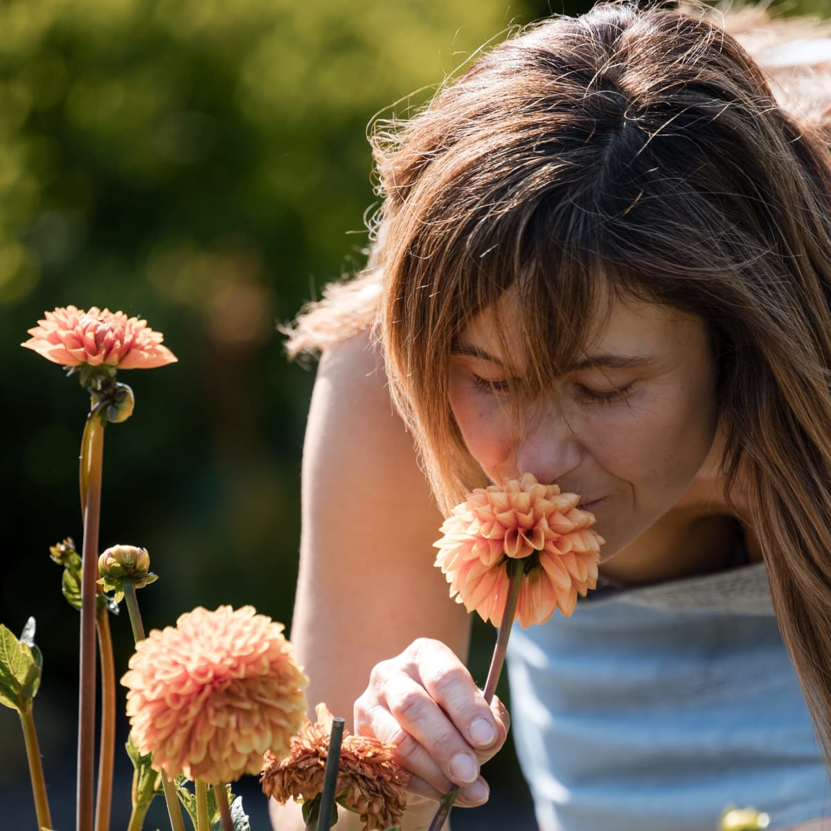 A teenage girl smelling a flower. 