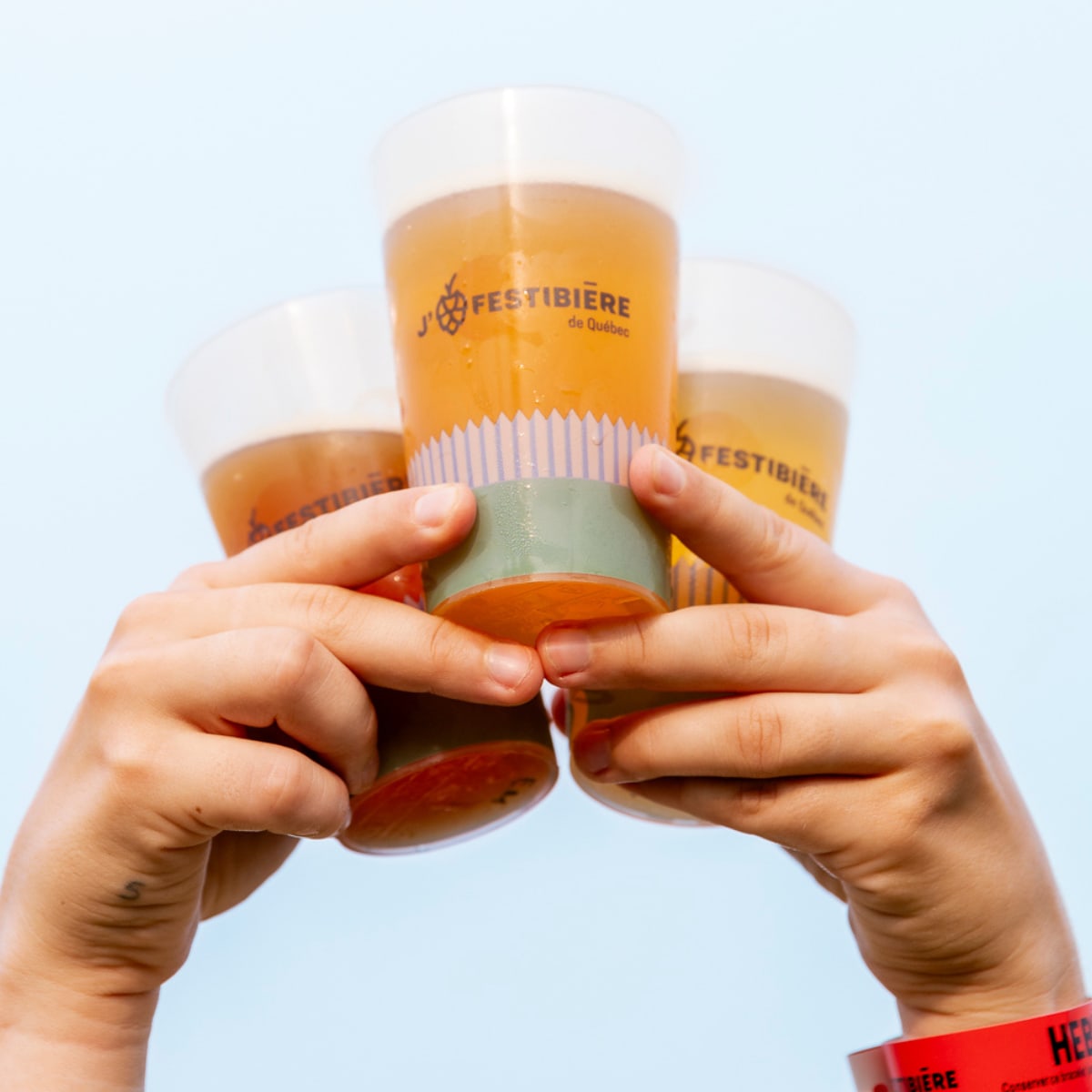 Le Festibière de Québec - Two hands hold three glasses filled with a liquid