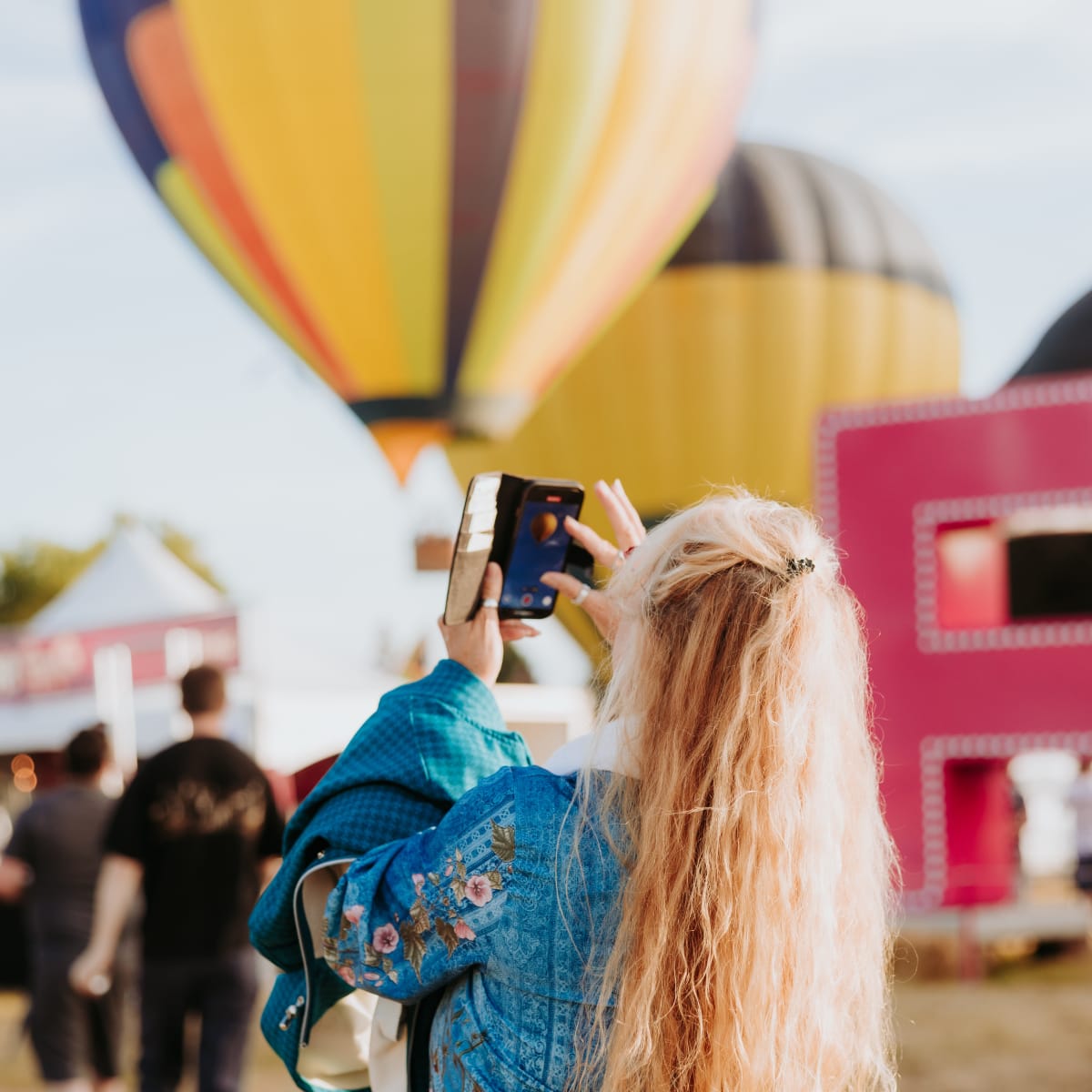 Woman taking a photo of a hot air balloon at the Gatineau Hot Air Balloon Festival.