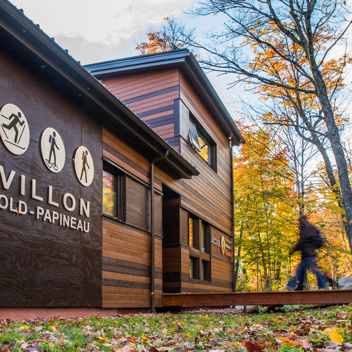 An adult walking toward a pavilion at Parc régional Montagne du Diable in the fall.